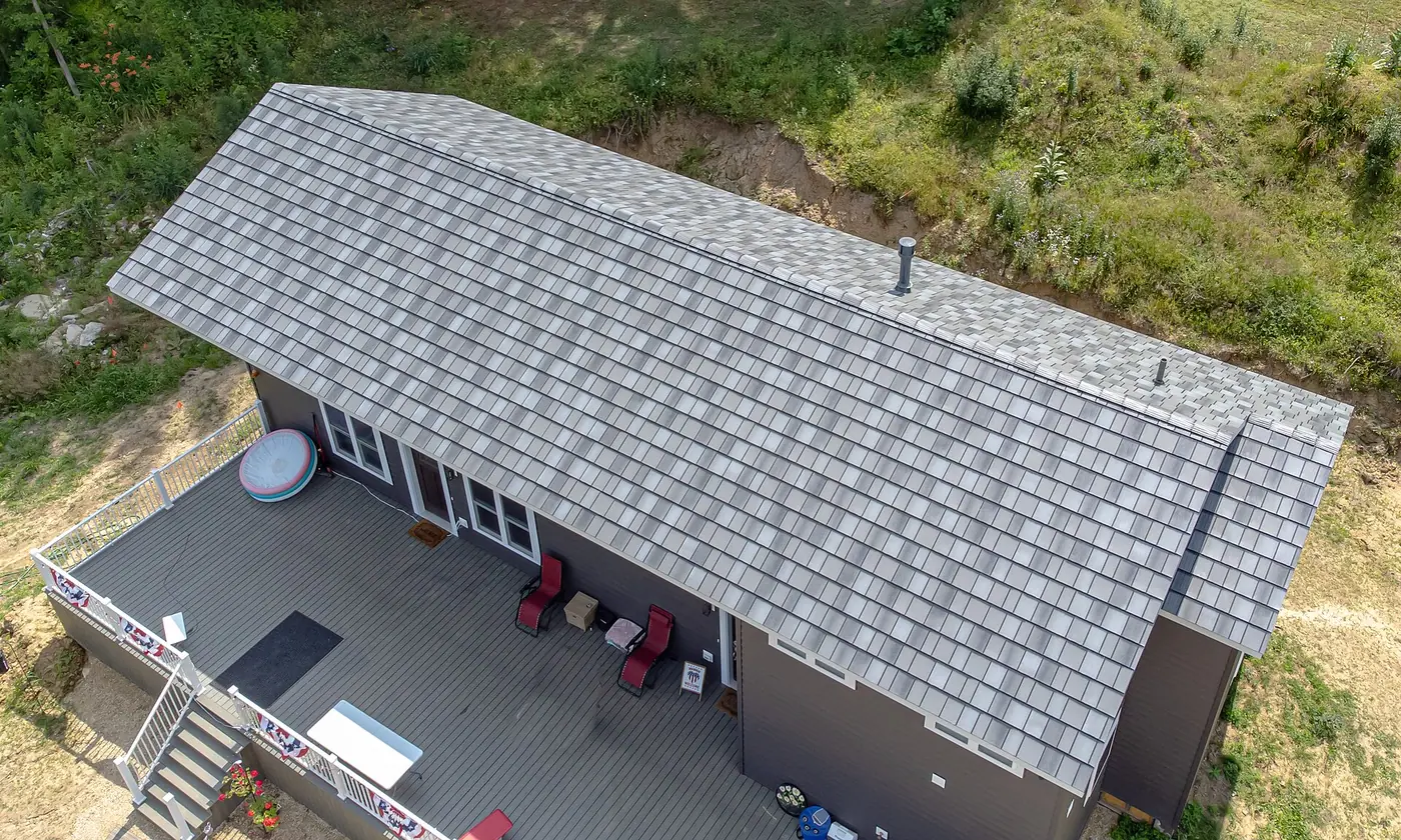 Aerial view of a new gray shingle roof on a house with a large back deck