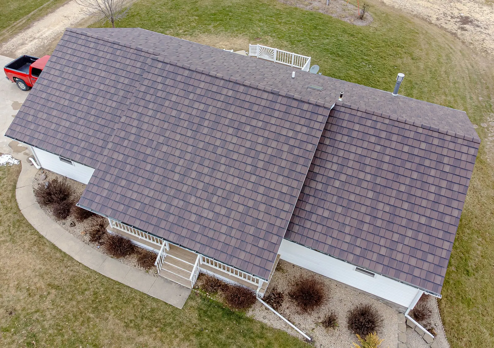 Aerial view of a ranch house with a brown laminated shingle-style roof filling most of the frame